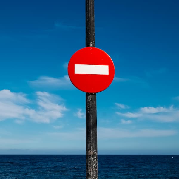 A red and white stop signage in front of a sea view.